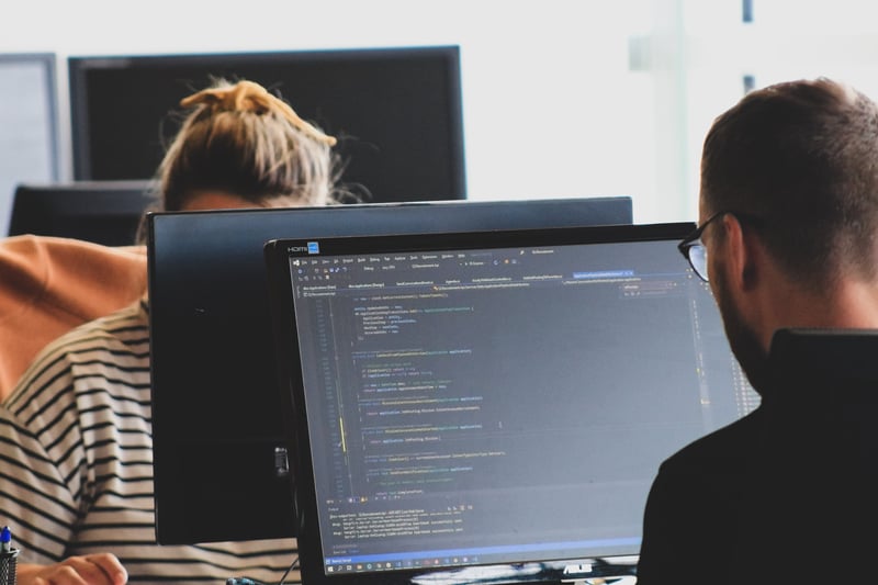 Image shows two people working at monitors facing each other